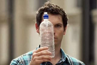 man looking at empty plastic water bottle